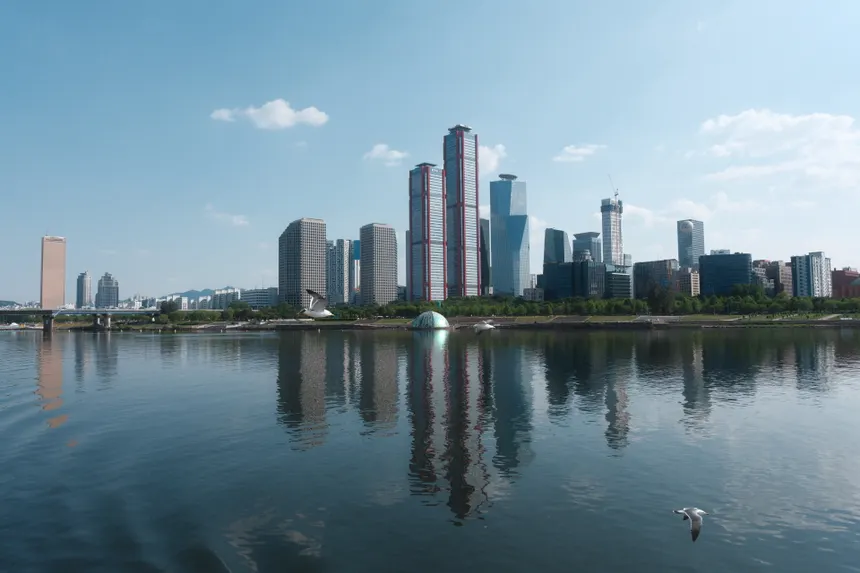 A stunning Seoul skyline reflecting in the river under a clear blue sky.
