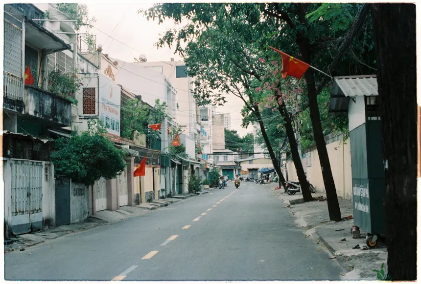 Quiet urban street lined with flags and trees, showcasing residential architecture in an Asian city.