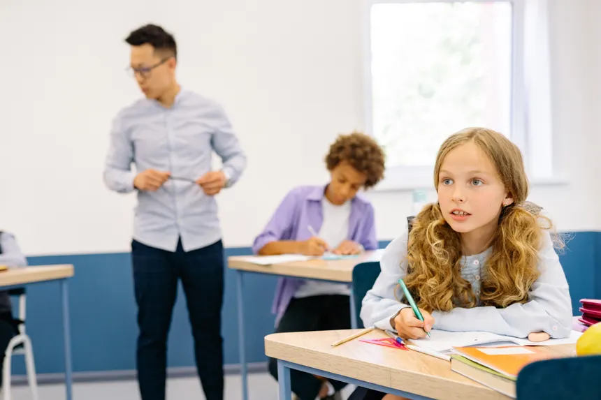 Students and teacher in a classroom focusing on study and interaction.