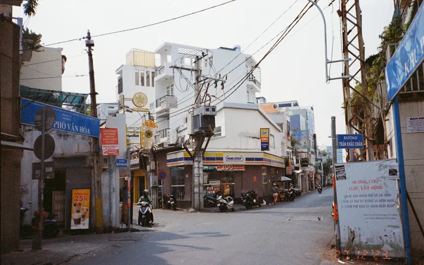 A bustling city street in Vietnam with motorbikes and buildings under a clear sky.