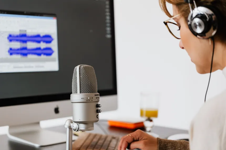 Woman using a microphone and headphones for audio recording at home office.