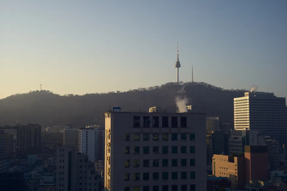 Skyline view of Seoul with Namsan Tower at sunset, highlighting urban landscape and iconic landmark.