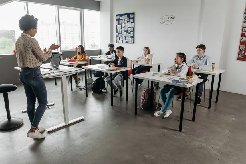 Teacher interacting with students in a modern classroom, fostering a diverse and engaging educational environment.