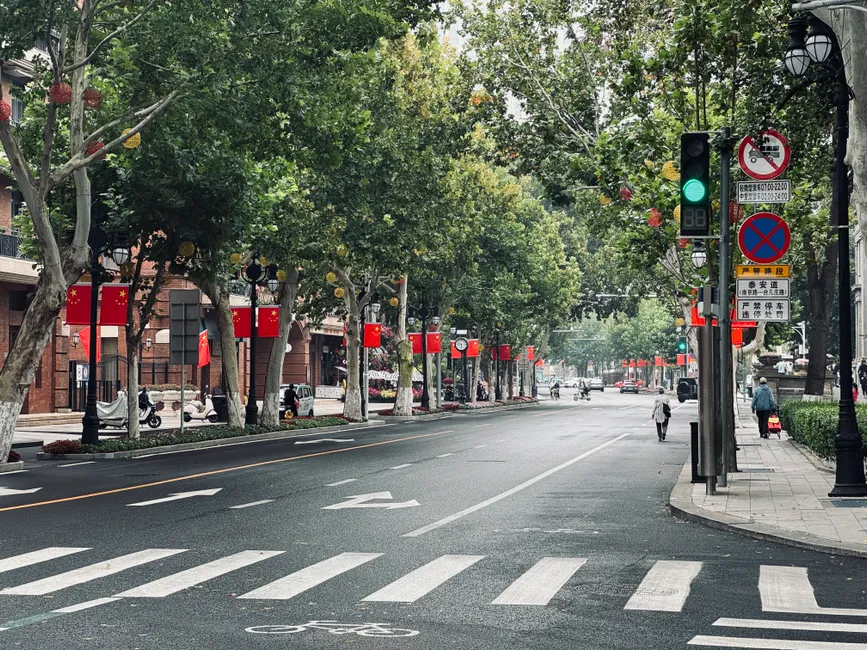 Tree-lined street adorned with Chinese flags in an urban setting, showcasing cultural ambiance.