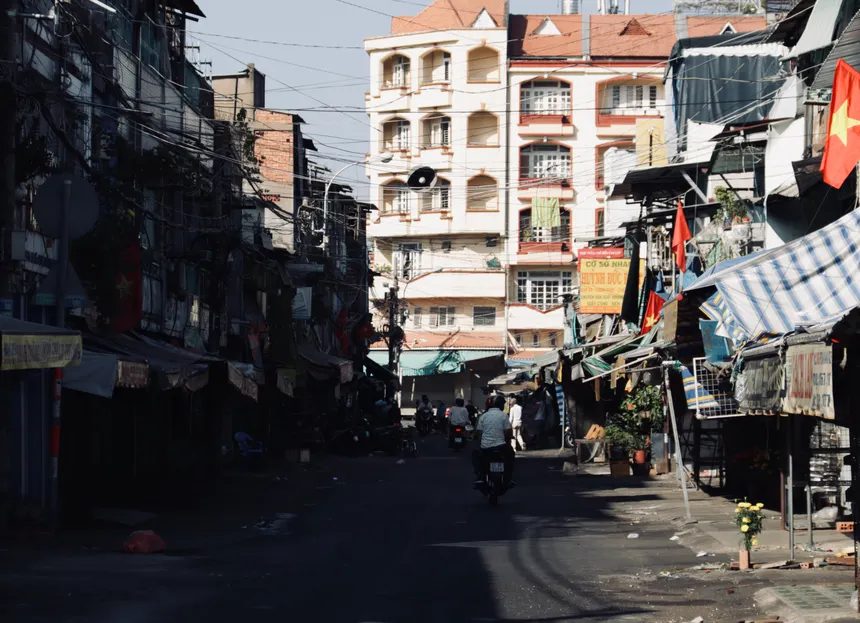 A lively street scene in Vietnam featuring buildings and vendors under clear daylight.