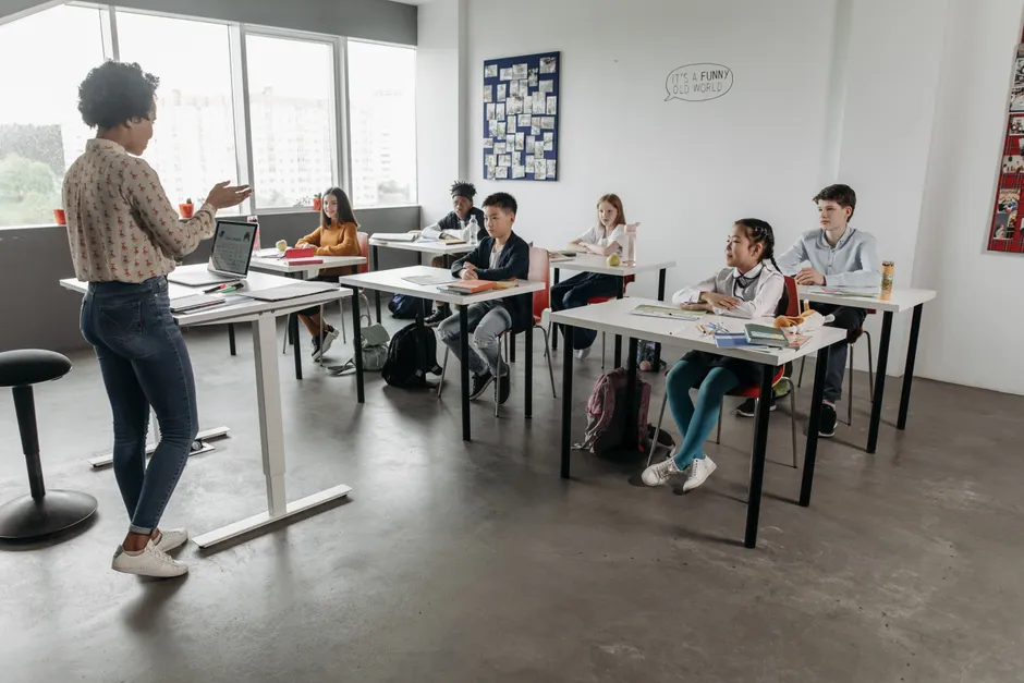 Teacher interacting with students in a modern classroom, fostering a diverse and engaging educational environment.