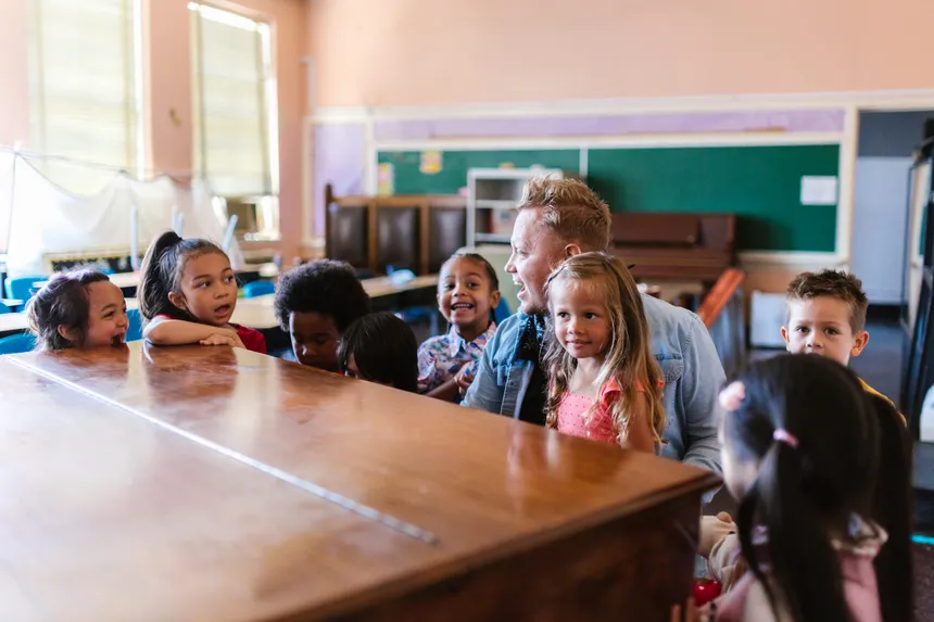 A group of children and a teacher enjoying a playful learning session in a classroom setting.