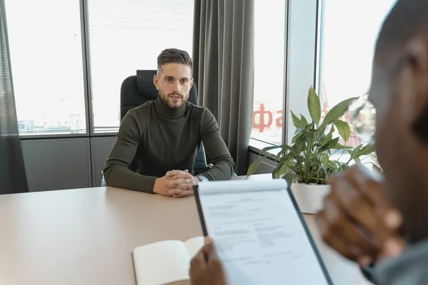 Professional man in turtleneck at office desk during an interview.